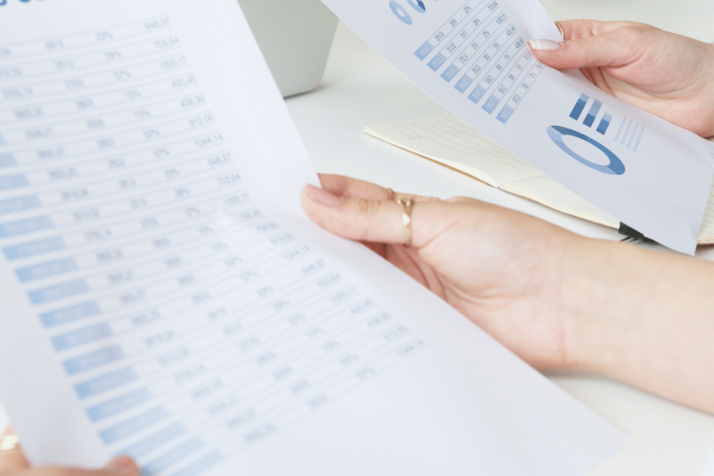Detailed view of a business professional reviewing statistical data on printed sheets.