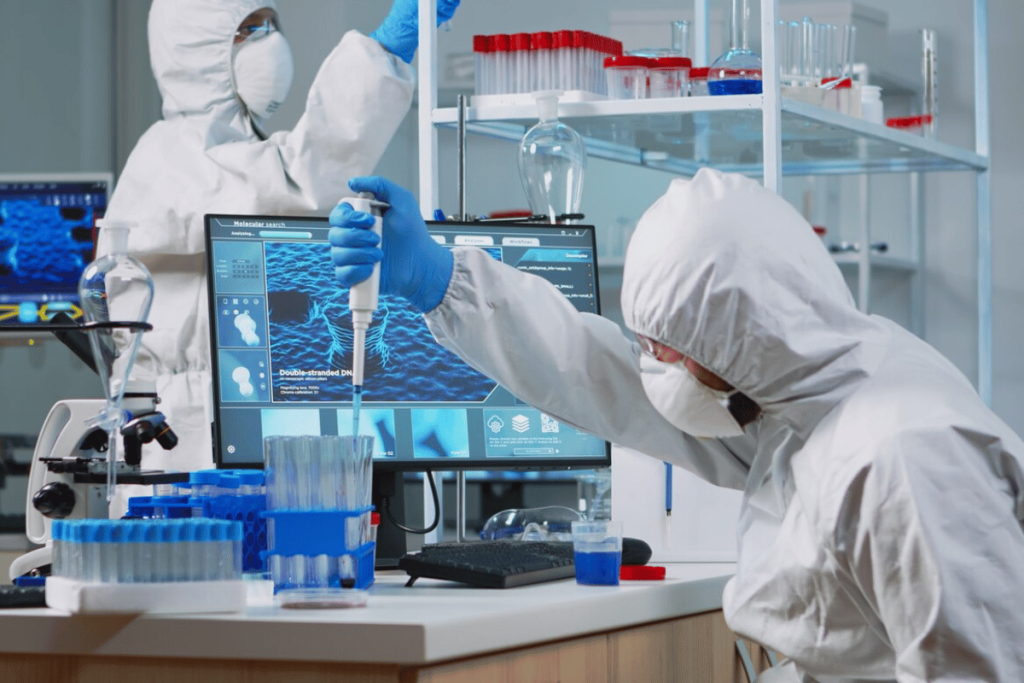 Two people in protective clothing working in a laboratory.