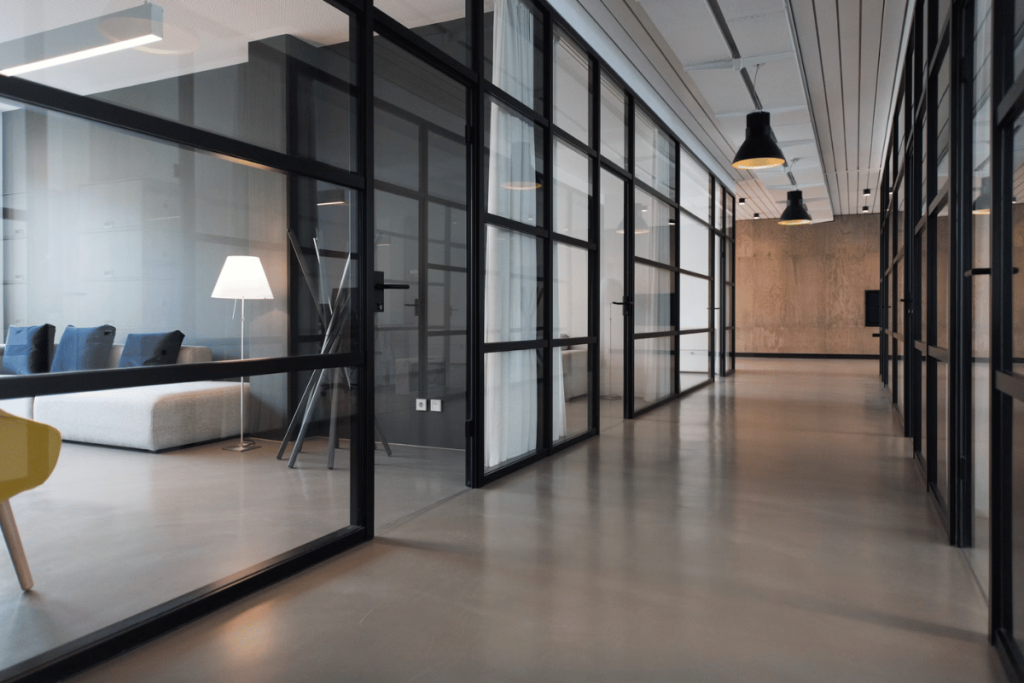 An office hallway with glass walls and chairs.